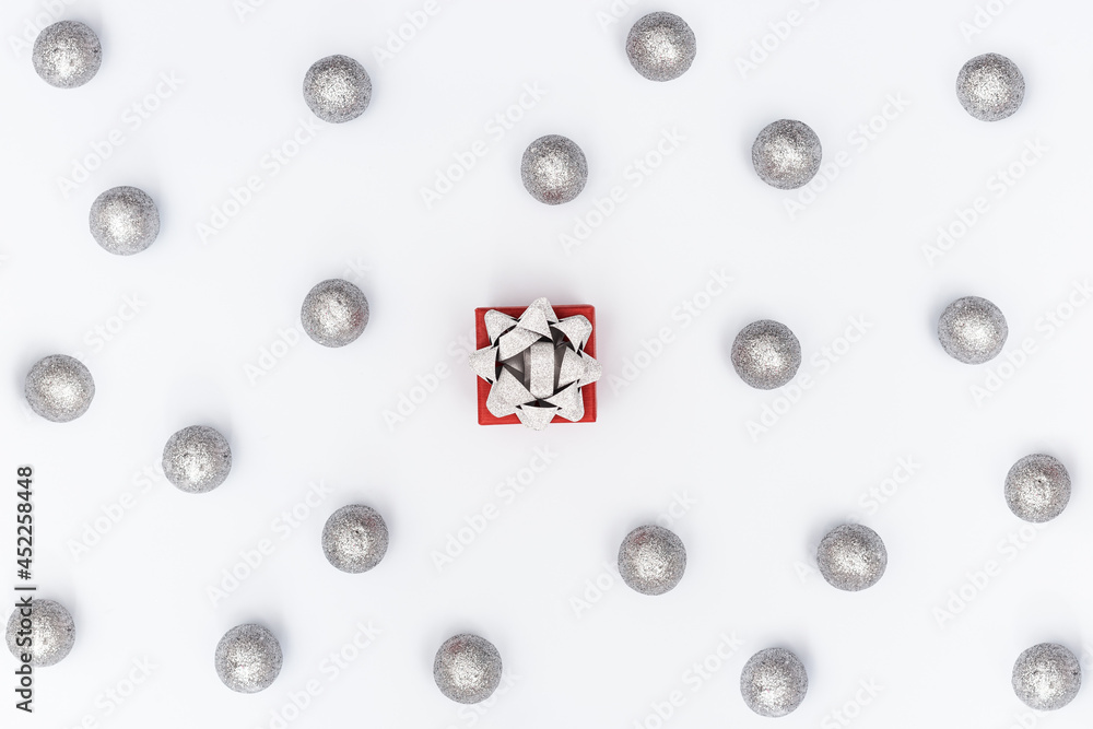 Christmas composition with silver shiny balls and gift box with surprise on white background. New Year holiday pattern