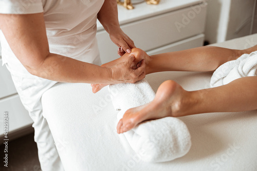 Young woman having foot massage procedure in spa salon