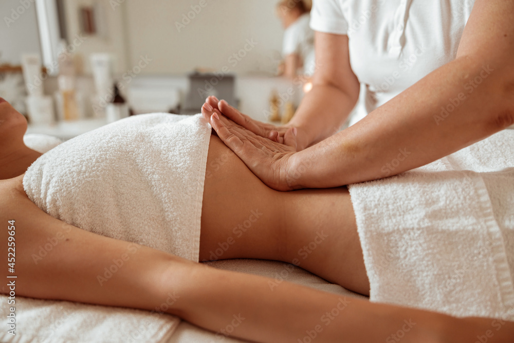 Fototapeta premium Masseuse hands massaging woman abdomen at wellness center