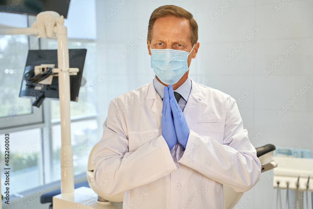 Fototapeta premium Expressive dentist making pleading gesture with his hands