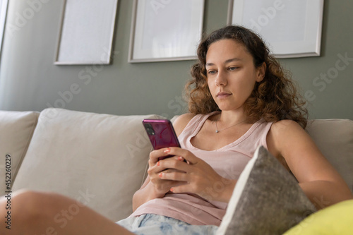 Young woman checking social media holding smartphone at home