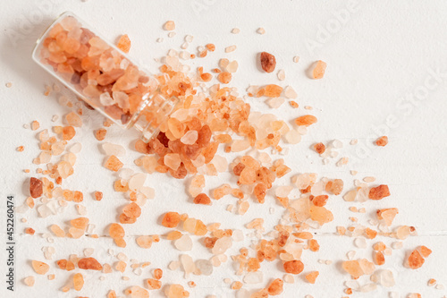 Himalayan pink salt for cooking in the glass bottle scattered on white background