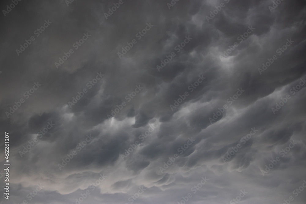 A wide angle cloudscape shot of dramatic clouds in a dark and stormy sky, a thunderstorm with backlit grey clouds, ominous and spooky