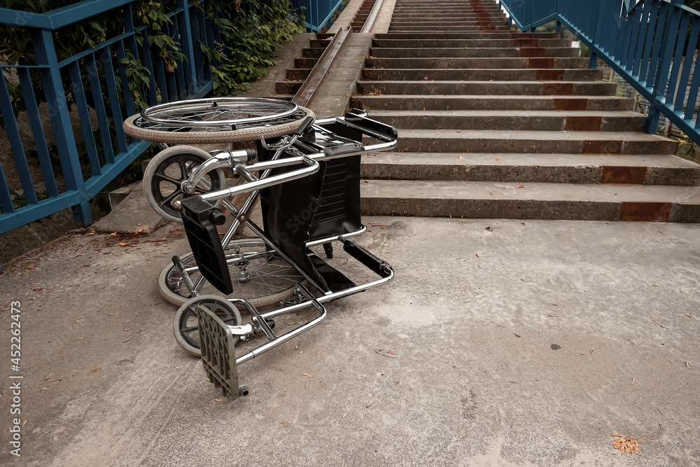 The concept of a wheelchair on the stairs turned over, disabled, full life, paralyzed. Problems for the disabled person.