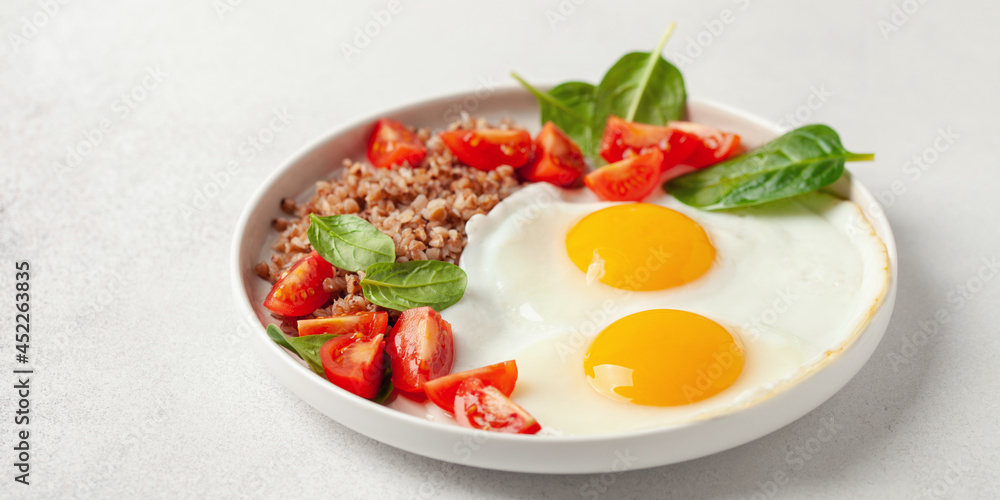 Eggs, buckwheat, tomatoes and spinach on a plate. Healthy breakfast. Eggs, buckwheat, tomatoes and spinach on a plate. Healthy breakfast.