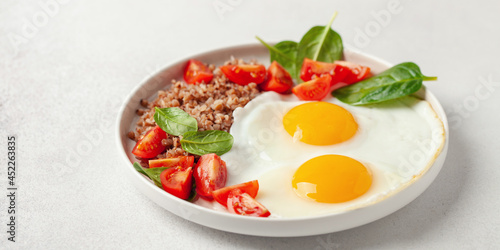 Eggs, buckwheat, tomatoes and spinach on a plate. Healthy breakfast.