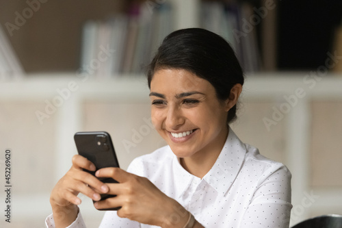 Indian woman hold cellphone enjoy remote chat comfort distant communication in social media. Happy user of e-business application, surfing information on internet. Modern tech usage, lifestyle concept