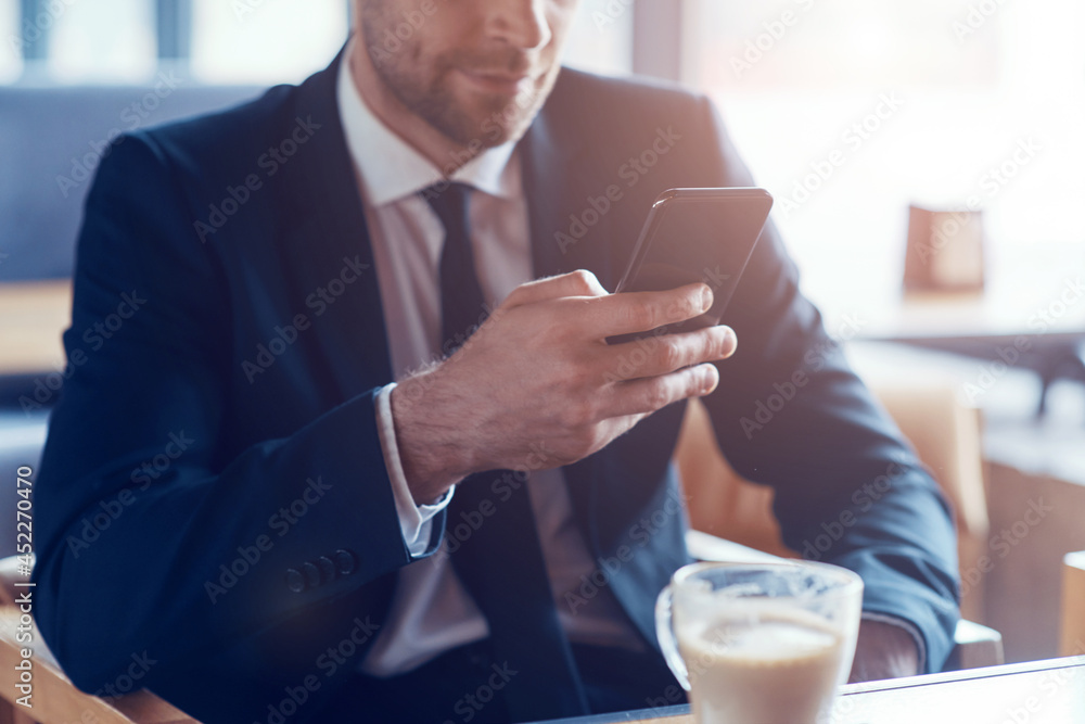 Close up of man in formalwear using smart phone while sitting in cafe Close up of man in formalwear using smart phone while sitting in cafe
