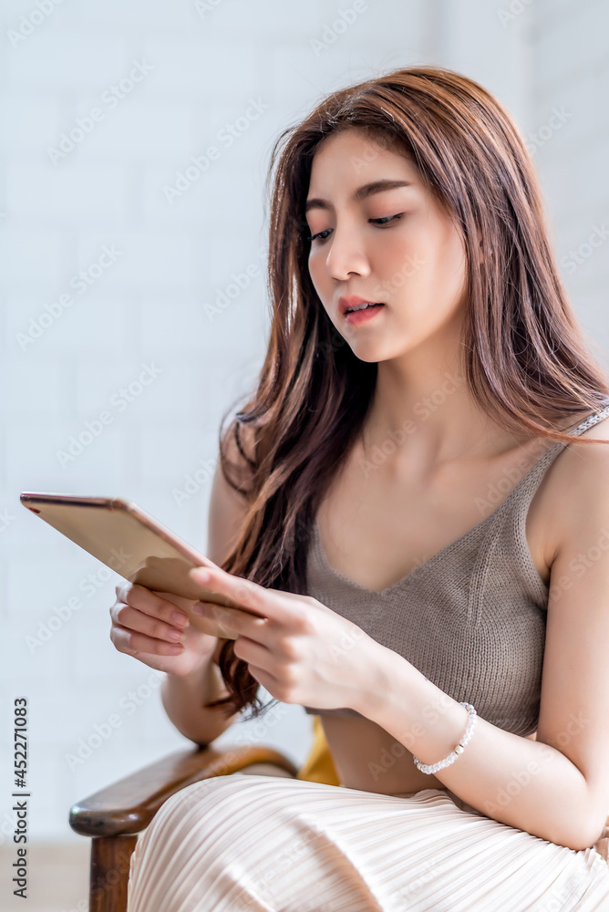 Young beautiful Asian woman sitting on blue sofa and reading web by tablet at living room in the morning
Young beautiful Asian woman sitting on blue sofa and reading web by tablet at living room in the morning
