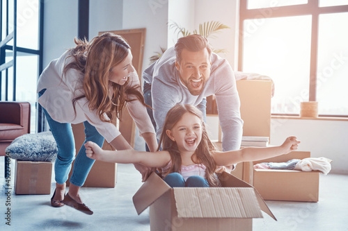 Cheerful young family smiling and unboxing their stuff while moving into a new apartment photo