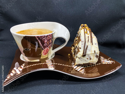 A cup of coffee on a saucer with a piece of Pancho cake