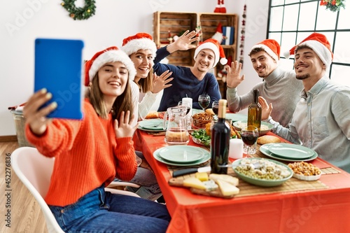 Group of young people having video call using laptop on christmas dinner at home.