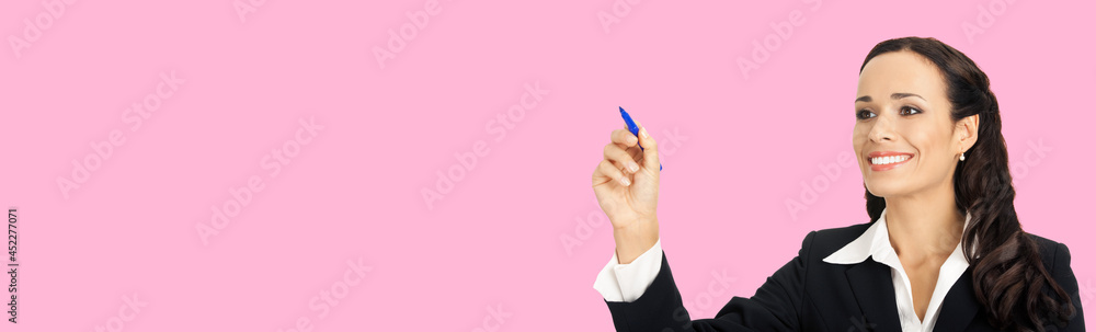Portrait of happy smiling beautiful young businesswoman in black confident suit, writing or drawing something on screen, by marker. Brunette woman, isolated over rose pink colour background Portrait of happy smiling beautiful young businesswoman in black confident suit, writing or drawing something on screen, by marker. Brunette woman, isolated over rose pink colour background