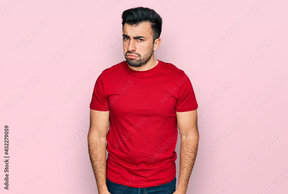 Hispanic man with beard wearing casual red t shirt skeptic and nervous, frowning upset because of problem. negative person.