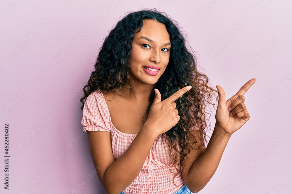 Young latin woman wearing casual clothes smiling and looking at the camera pointing with two hands and fingers to the side. Young latin woman wearing casual clothes smiling and looking at the camera pointing with two hands and fingers to the side.
