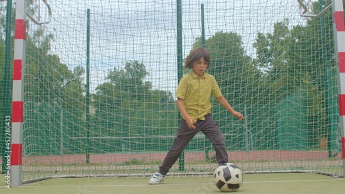 A teenager prepares to catch a soccer ball in goal. One misses a goal, a point. He misses the ball with his foot. Active play, training of attention and reaction.