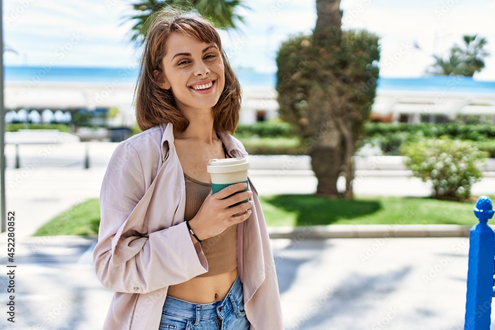 Young caucasian girl smiling happy drinking coffee at the city.