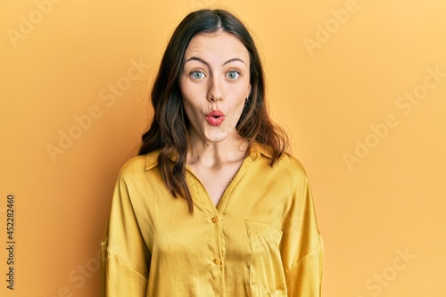 Young brunette woman wearing casual yellow shirt scared and amazed with open mouth for surprise, disbelief face © Krakenimages.com