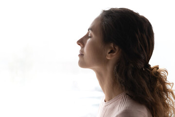 Profile face view of beautiful young 30s woman close up. Serene female closed her eyes breath fresh air, take break pose on white background, stress free, relaxation, negative emotions relief concept