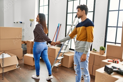 Young latin couple smiling happy standing with hands together at new home.