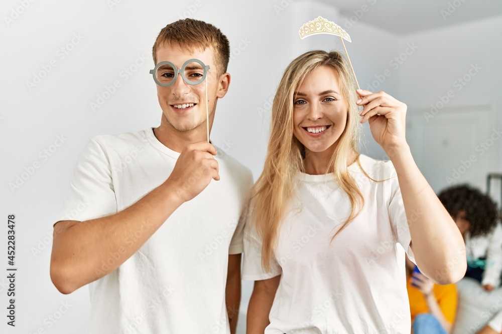 Two young friends having party using funny costume accessories at home.