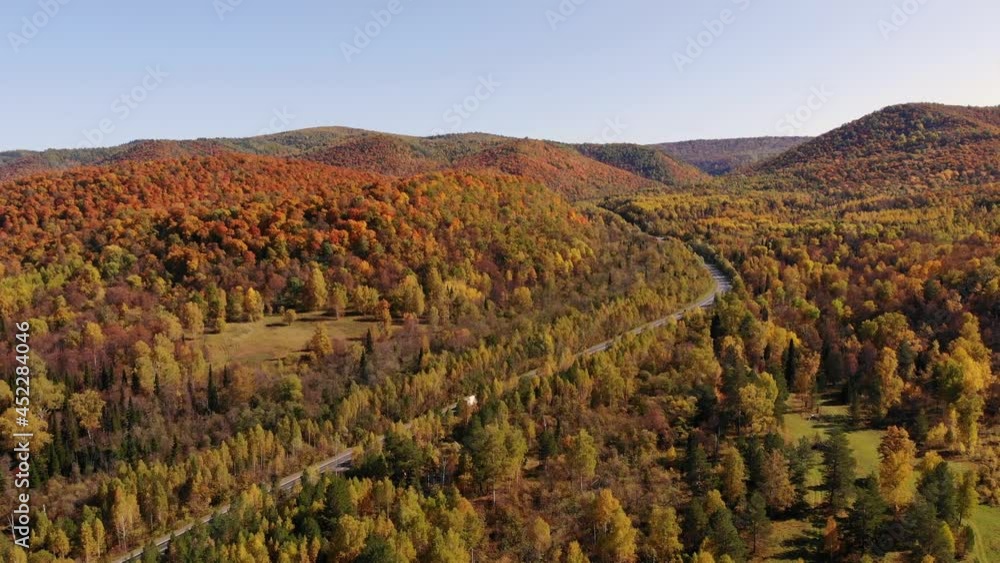 Aerial view. A picturesque autumn highway on which a white truck is driving. Autumn nature.Highway going into the distance. Aerial view. A picturesque autumn highway on which a white truck is driving. Autumn nature.Highway going into the distance.