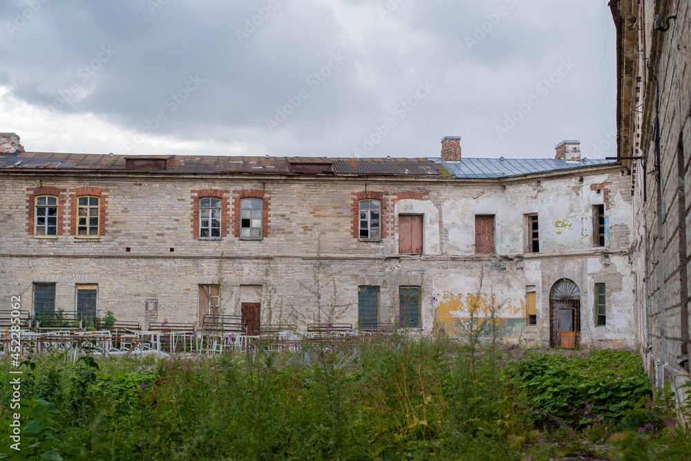 Courtyard of abandoned Patarei prison (Estonian - Patarei Vangla). Concrete prison wall against a cloudy sky.