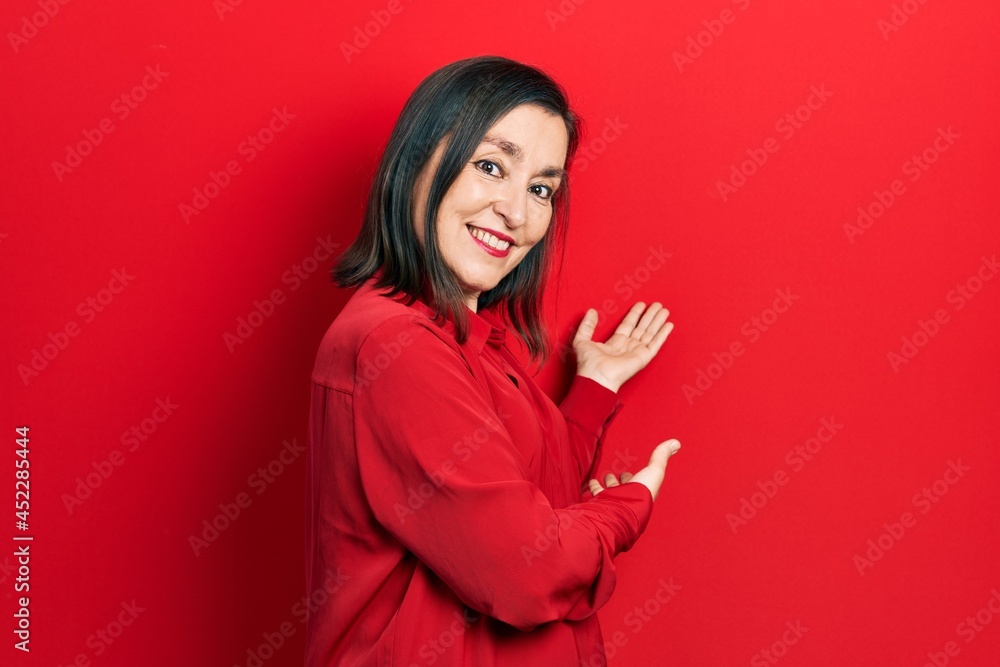 Middle age hispanic woman wearing casual clothes inviting to enter smiling natural with open hand Middle age hispanic woman wearing casual clothes inviting to enter smiling natural with open hand