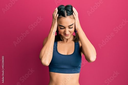 Young brunette girl wearing sportswear and braids suffering from headache desperate and stressed because pain and migraine. hands on head.