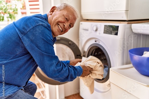 Senior caucasian man smiling happy doing laundry at the terrace.