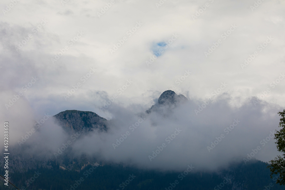 Obraz premium Zugspitze mountain massif disappearing in fog and clouds with dramatic sky. Copy space. Template for travel and touism concept.
