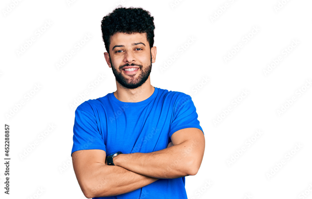 Obraz premium Young arab man with beard wearing casual blue t shirt happy face smiling with crossed arms looking at the camera. positive person.