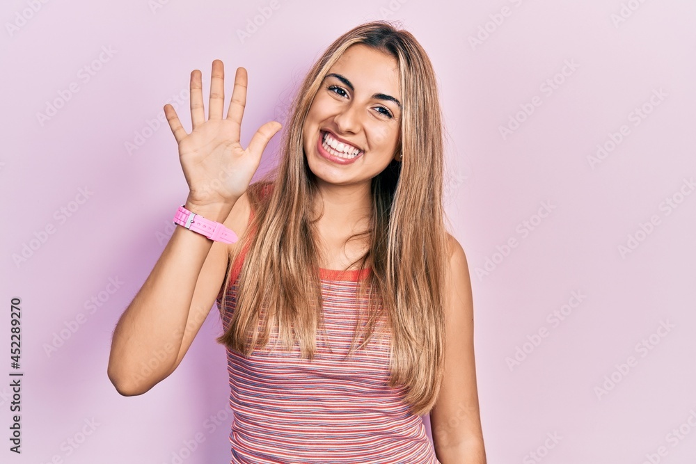Beautiful hispanic woman wearing casual summer t shirt showing and pointing up with fingers number five while smiling confident and happy. Beautiful hispanic woman wearing casual summer t shirt showing and pointing up with fingers number five while smiling confident and happy.