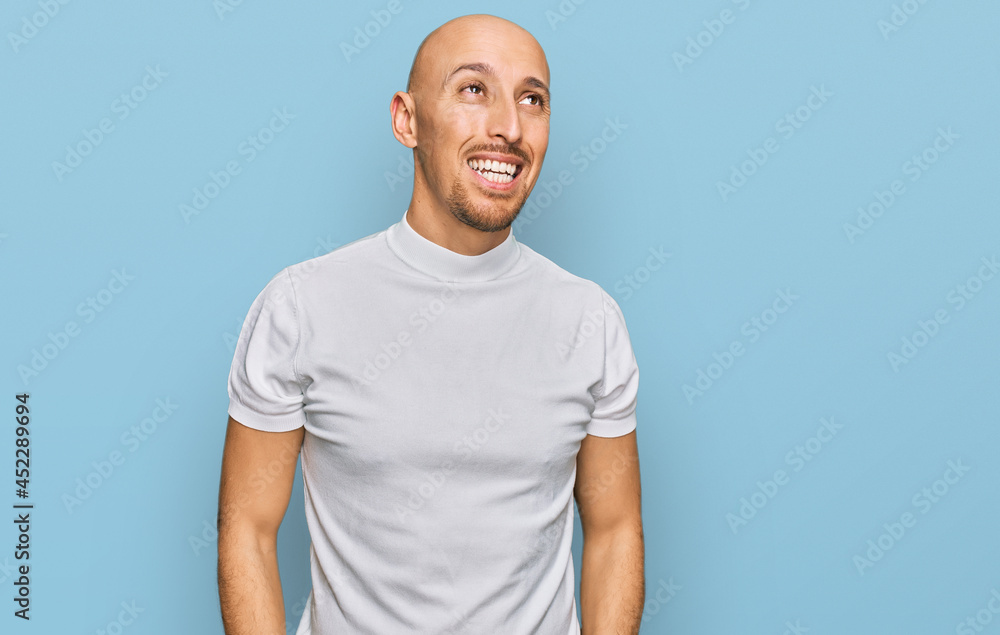 Bald man with beard wearing casual white t shirt looking away to side with smile on face, natural expression. laughing confident. Bald man with beard wearing casual white t shirt looking away to side with smile on face, natural expression. laughing confident.
