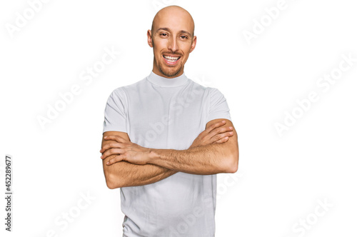 Bald man with beard wearing casual white t shirt happy face smiling with crossed arms looking at the camera. positive person.
