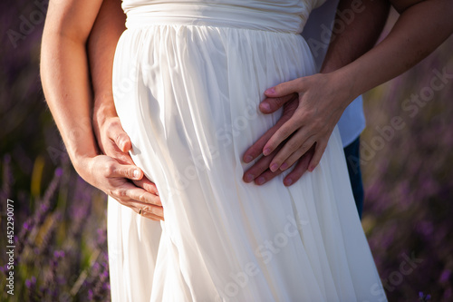 Pregnant woman and man hugs outdoor 