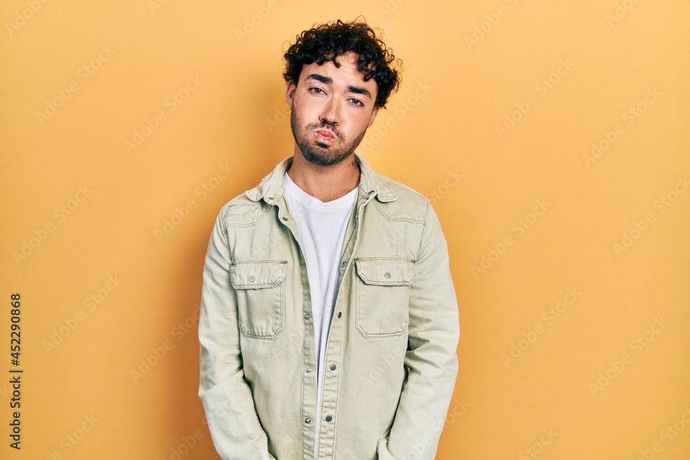 Young hispanic man wearing casual clothes puffing cheeks with funny face. mouth inflated with air, crazy expression. Young hispanic man wearing casual clothes puffing cheeks with funny face. mouth inflated with air, crazy expression.