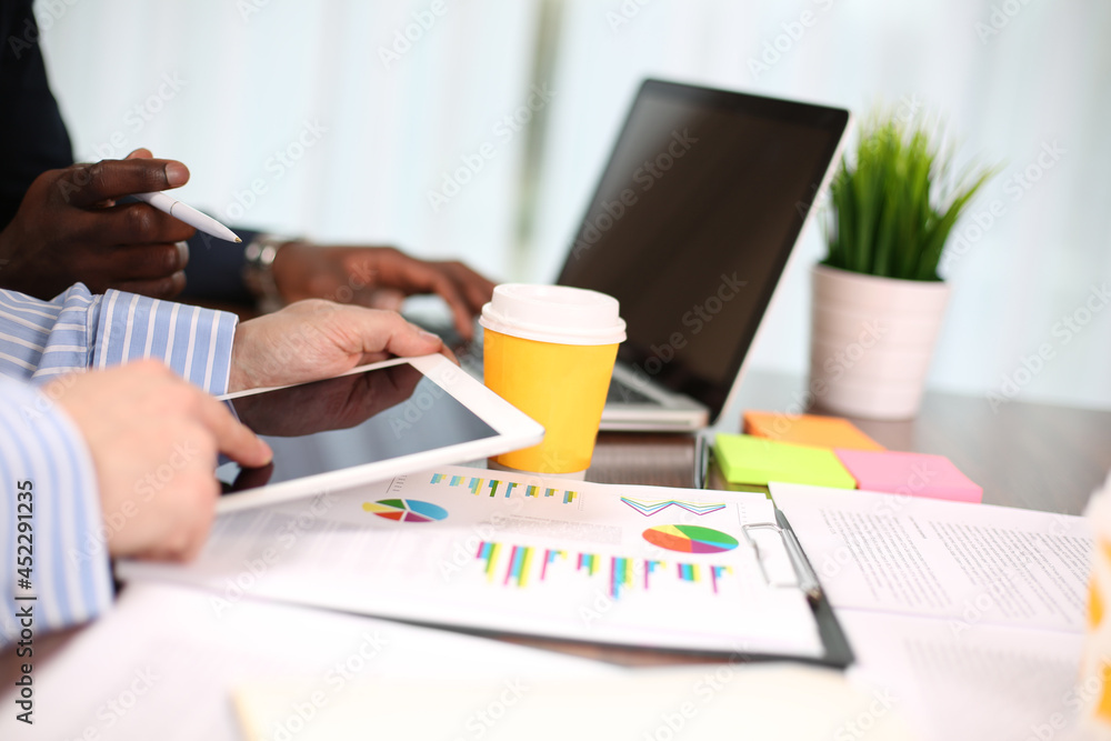 Image of two young businessmen using touchpad at meeting Image of two young businessmen using touchpad at meeting