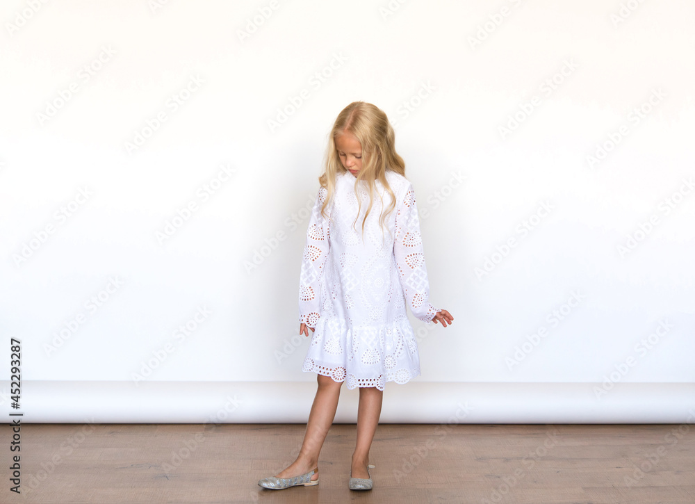 Beautiful girl in a white dress on isolated white background. Blonde with long hair. Emotions. Beautiful girl in a white dress on isolated white background. Blonde with long hair. Emotions.