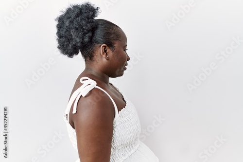 Young african woman standing over white isolated background looking to side, relax profile pose with natural face and confident smile.
