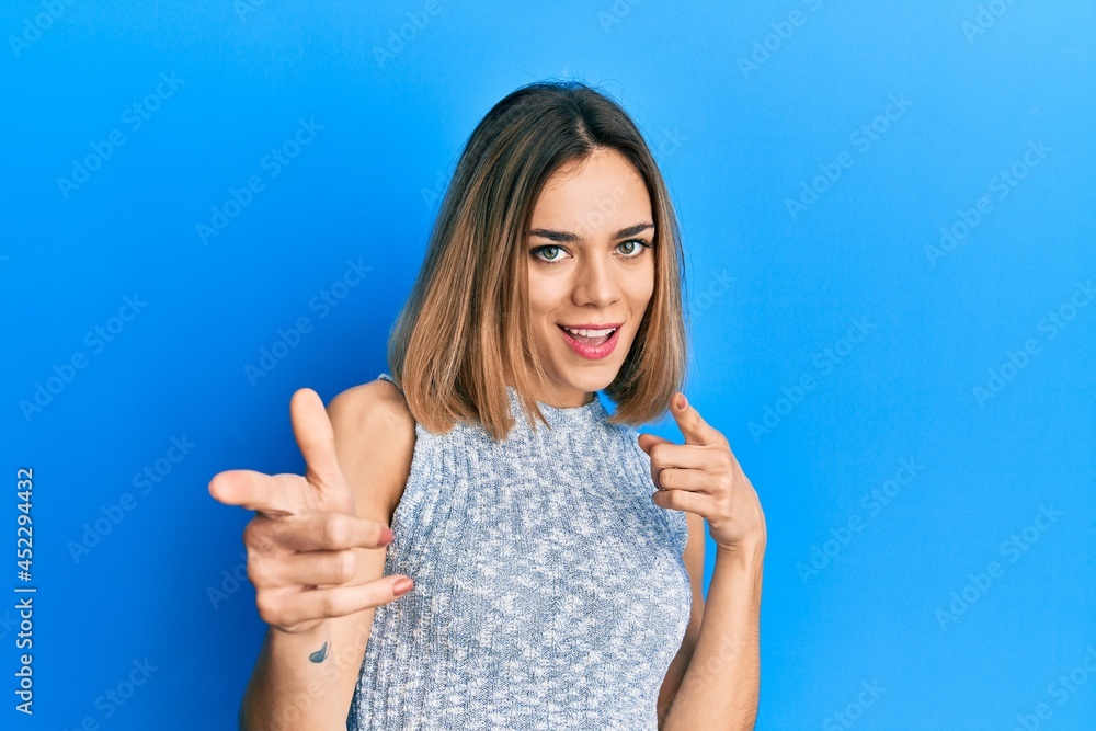 Young caucasian blonde woman wearing casual t shirt pointing fingers to camera with happy and funny face. good energy and vibes. Young caucasian blonde woman wearing casual t shirt pointing fingers to camera with happy and funny face. good energy and vibes.