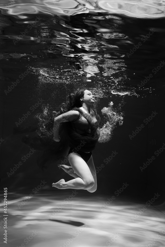 Fototapeta premium Beautiful girl underwater in the pool. Black and white photography, creative and mystical