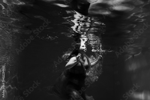 Beautiful girl underwater in the pool. Black and white photography, creative and mystical