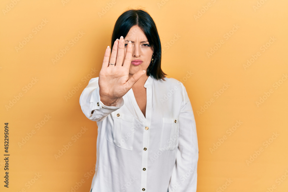 Young hispanic woman wearing casual clothes doing stop sing with palm of the hand. warning expression with negative and serious gesture on the face. Young hispanic woman wearing casual clothes doing stop sing with palm of the hand. warning expression with negative and serious gesture on the face.