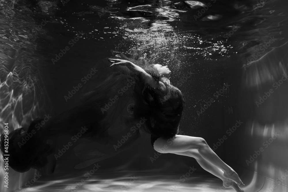 Fototapeta Beautiful girl underwater in the pool. Black and white photography, creative and mystical