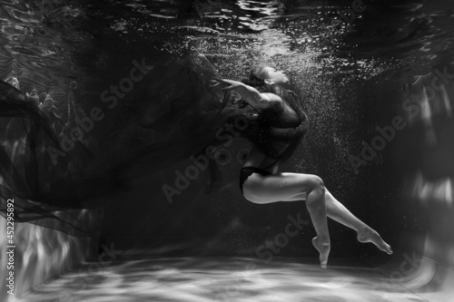 Beautiful girl underwater in the pool. Black and white photography, creative and mystical