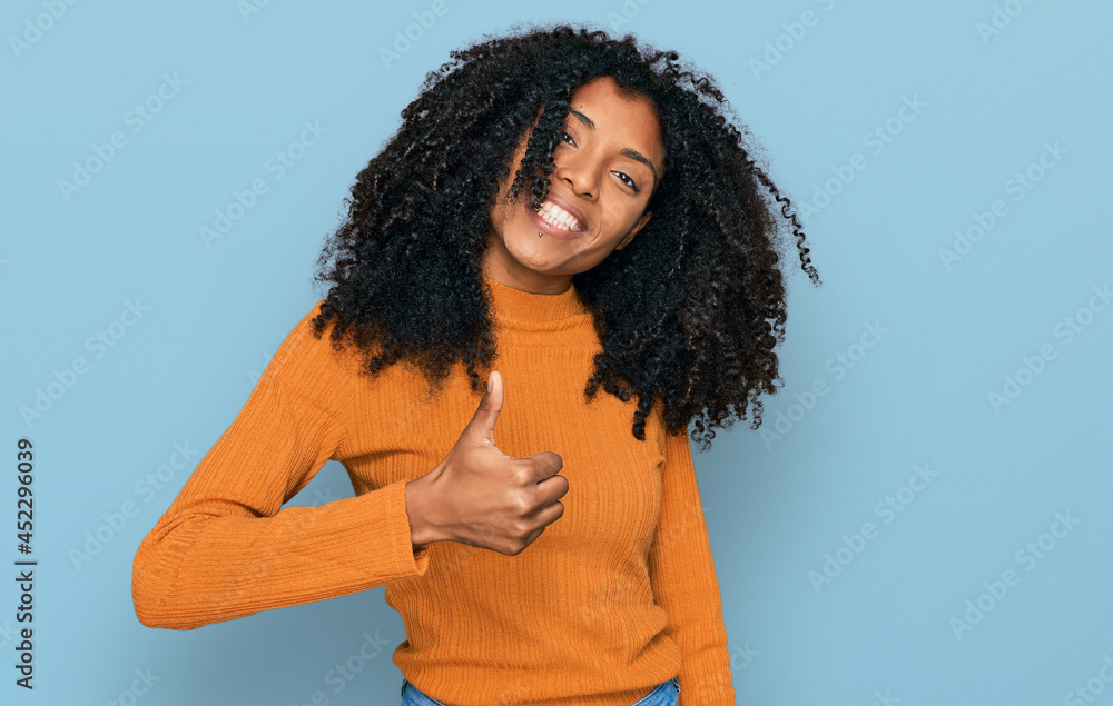 Young african american girl wearing casual clothes doing happy thumbs up gesture with hand. approving expression looking at the camera showing success. Young african american girl wearing casual clothes doing happy thumbs up gesture with hand. approving expression looking at the camera showing success.