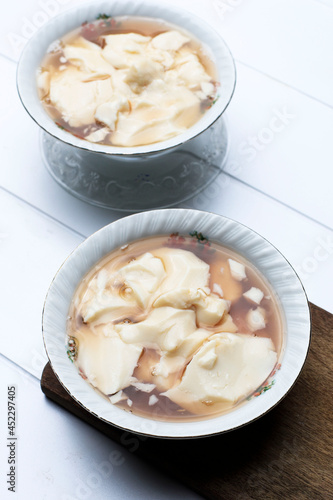 Tahwa or Wedang Tahu or Kembang Tahu, Indonesian Traditional Dessert made from Gingger and Palm Sugar Syrup with Beancurd Made from Soy Bean Milk. Serve on Bowl, Top View with Copy Space for Text photo