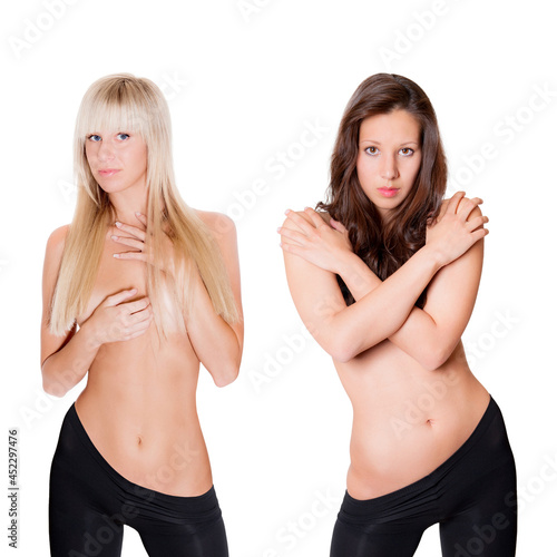 Two beautiful topless women with long hair wearing black leggings, isolated in front of white studio background