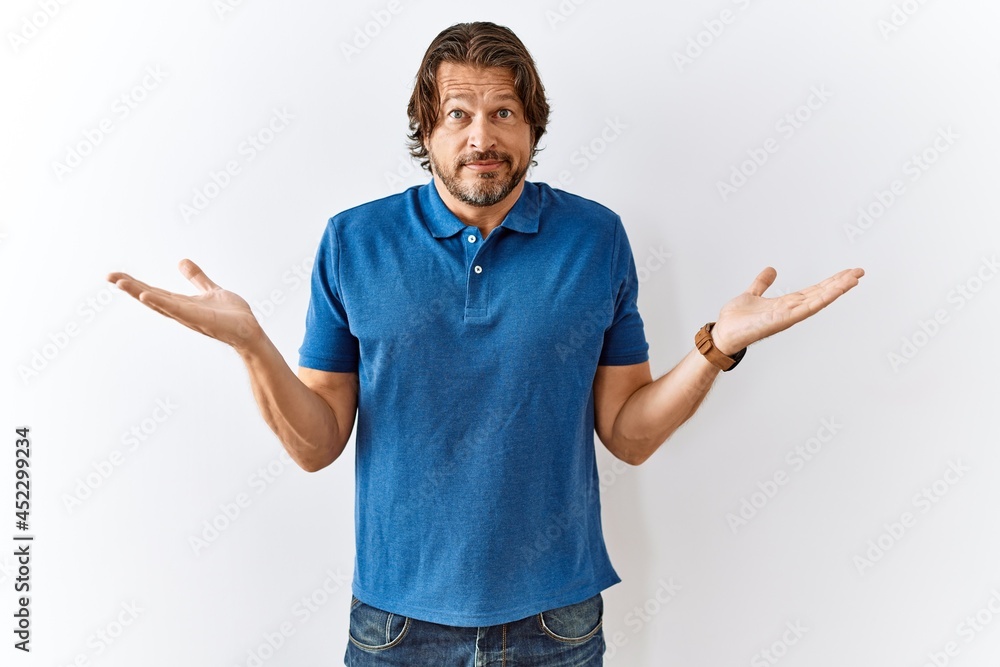 Fototapeta premium Handsome middle age man standing together over isolated background clueless and confused expression with arms and hands raised. doubt concept.